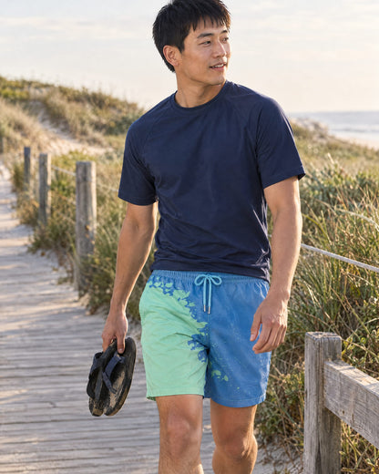 Man on a boardwalk in Shift Blue to Green swim shorts