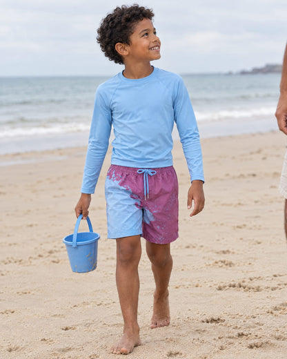 Boy with a bucket on the beach in Shift kids' Purple to Blue swim shorts