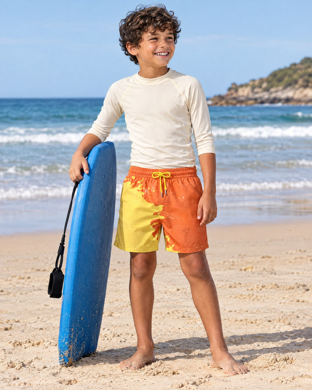 Boy with a bodyboard on the beach in Shift kids' Orange to Yellow swim shorts