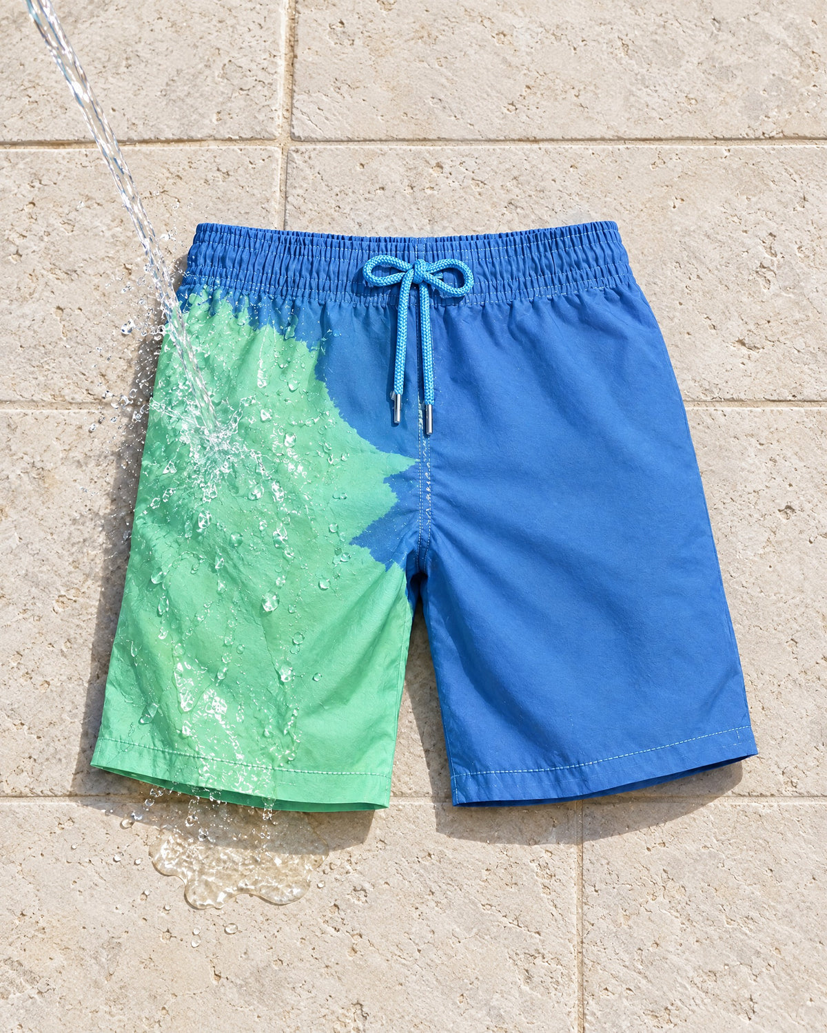Water poured on The Original swim shorts, turning blue to green on pool tiles