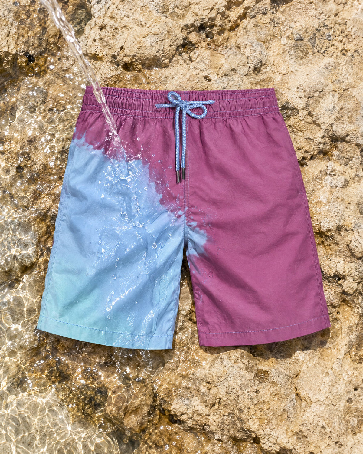 Water poured on The Original swim shorts, turning purple to blue on a rock pool ledge