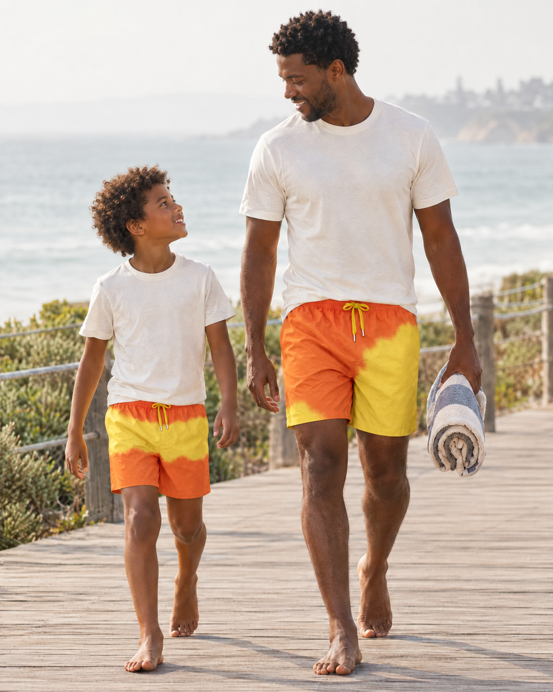 Dad and son walking a beach boardwalk in matching Shift Orange to Yellow swim shorts