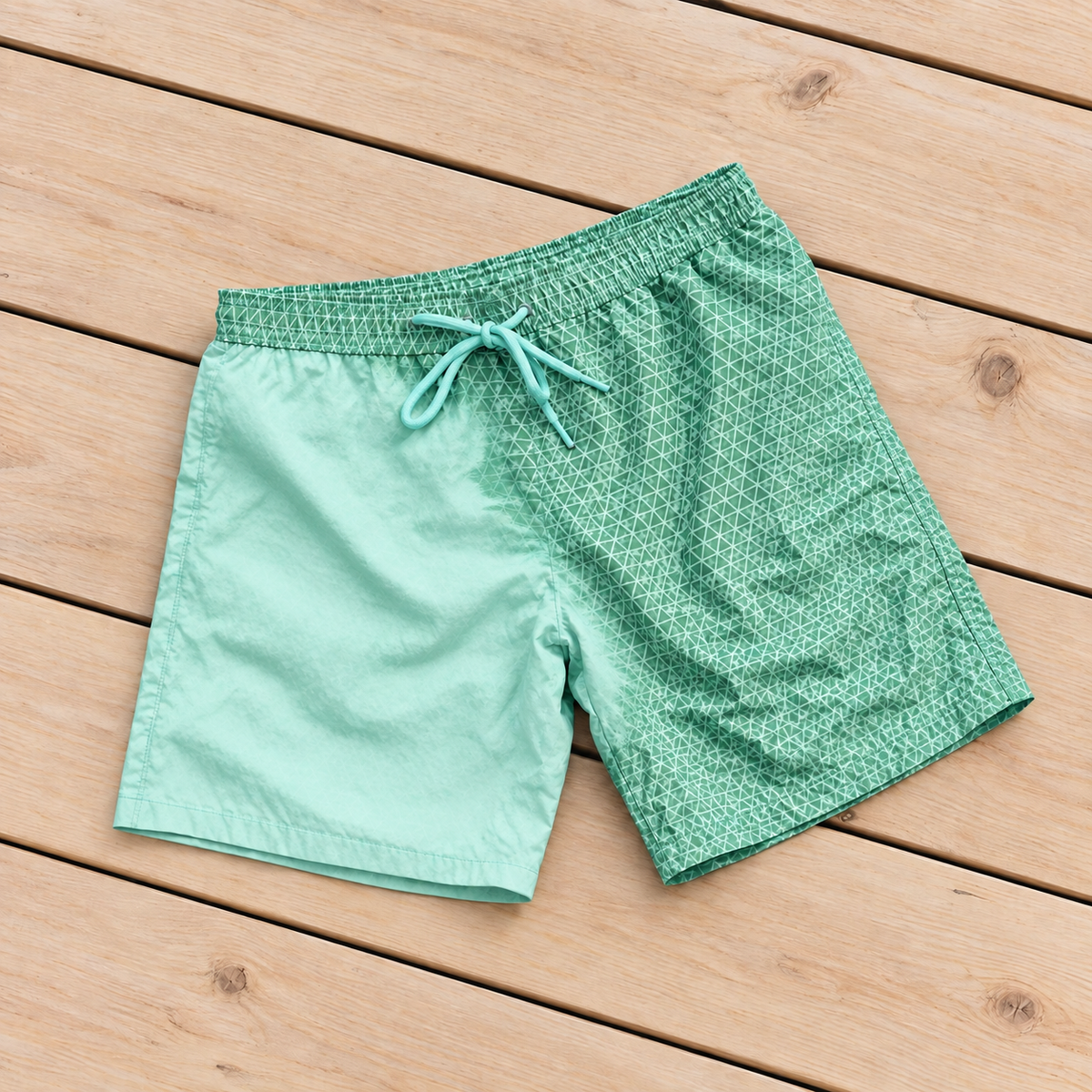 Shift Geometric colour-changing swim shorts, Green to Mint, on a timber deck
