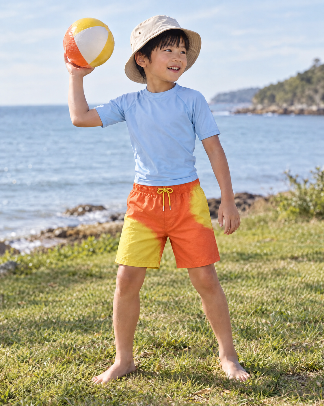 Boy with a beach ball in Shift kids Orange to Yellow swim shorts