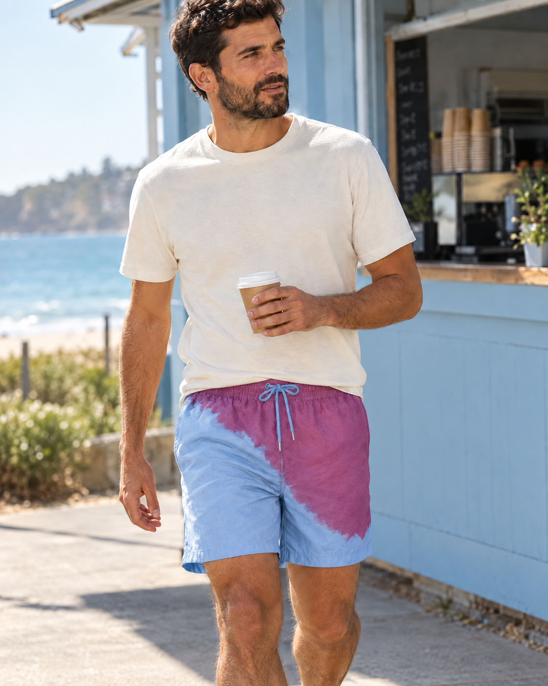 Man at a beach kiosk in Shift Purple to Blue swim shorts