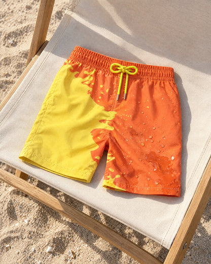 Shift kids' Orange to Yellow swim shorts on a beach chair, showing both colours