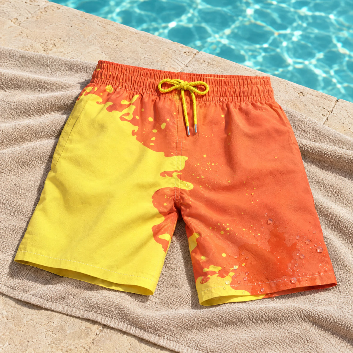 Shift Orange to Yellow swim shorts on a poolside towel, showing both colours